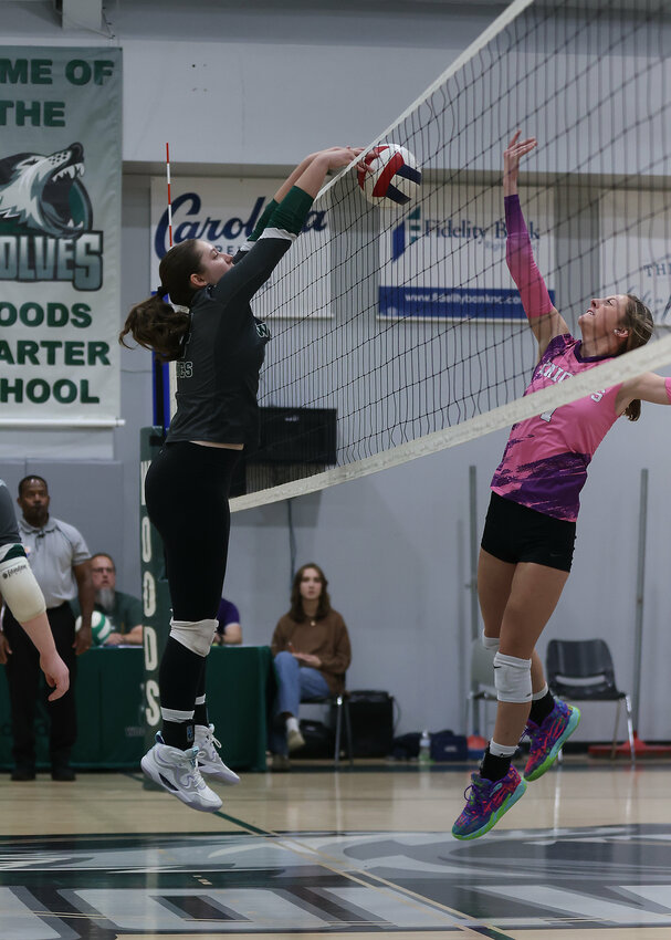 Woods Charter (left) and Chatham Charter meet at the net in a volleyball showdown last fall. The two schools were initially separated in the conference realignment but now are back in the same league.