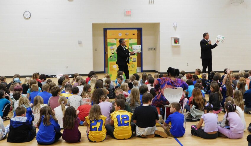 Larson Elementary students listen attentively Sept. 29 as State Fire Marshal Kevin Sehlmeyer reads to them about the perils of inviting a dragon to tea.