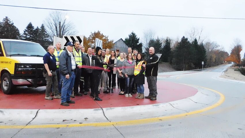 Surrounded by a crowd of Clare County Road Commission personnel, county dignitaries and well-wishers, CCRC Chairperson Karen Hulliberger snips the ribbon Oct. 27, officially opening the county&rsquo;s first roundabout at the Surrey Road/Old State Avenue intersection.