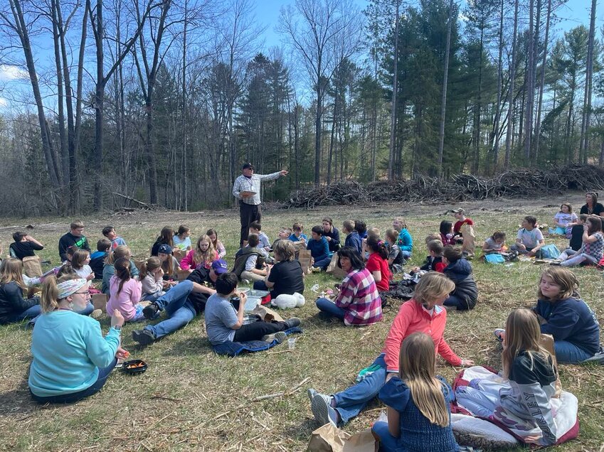 Steve Scoville, superintendent of Farwell Schools read two books to third-graders as they ate their brown bag lunch as part of the Earth Day activities in the school forest.