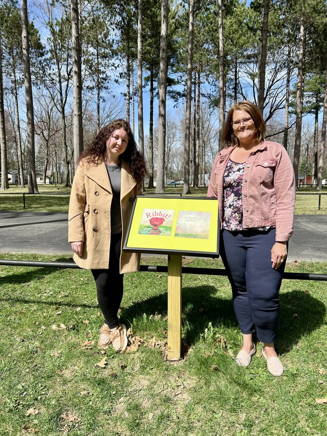Euri Garcia and Sarah McCurdy stand proudly at the storybook stroll’s opening podium, showcasing Ribbit!’s first page at Harrison City Park, April 30, 2025.