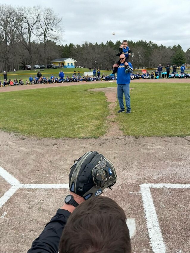 Young Benjamin, grandson of this year’s first pitch honoree Bryan Umphrey, lofts the first pitch of the Harrison Little League season.