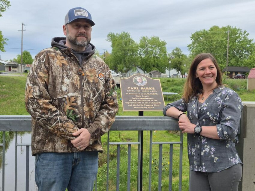 Danny and Allyson Parks pose with the plaque dedicated to their father Carl Parks at the Sixth Street Bridge in Clare.