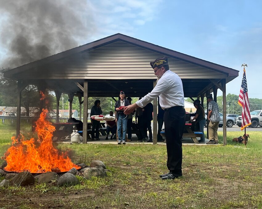 Post Commander Scott Taylor (Army) places a flag for incineration, and Ralph Powell (Marine Corps) offers a respectful salute.