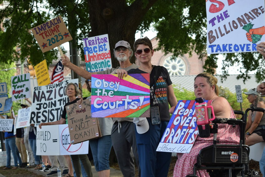 Angel Lee, right, and Karina Williams, center, both of Columbia, joined a May Day protest outside the post office in downtown Columbia, Thursday, May 1, 2025. (Photo by Jessica Holdman/SC Daily Gazette)