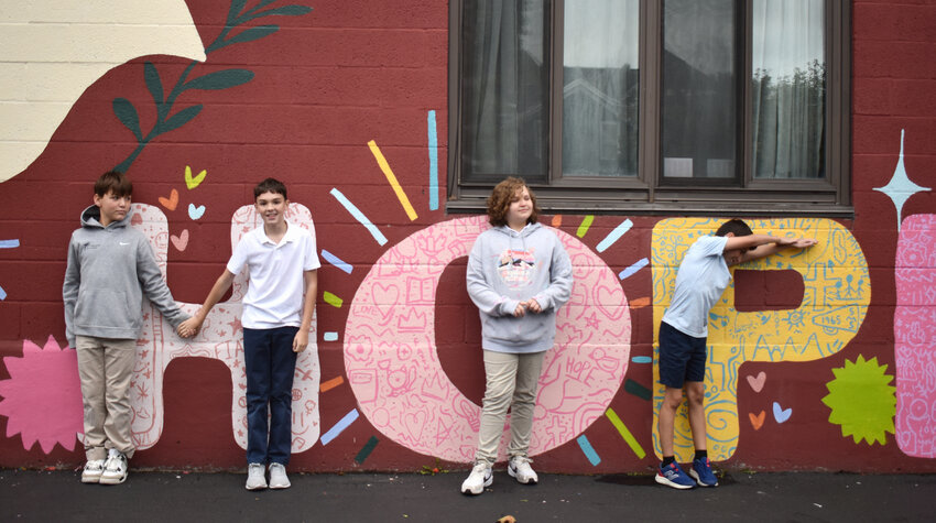 Jimmy Peart, left, Owen Gallup, Emma Williams and Lucian Fischer show off their doodles they contributed to their mural at St. Marys Catholic School.