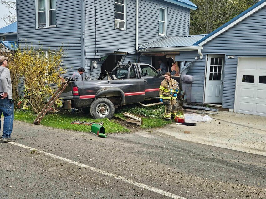 Firefighters evaluate the scene Friday after a pickup truck crashed into a house on Blodgett Mills Road West in Blodgett Mills.