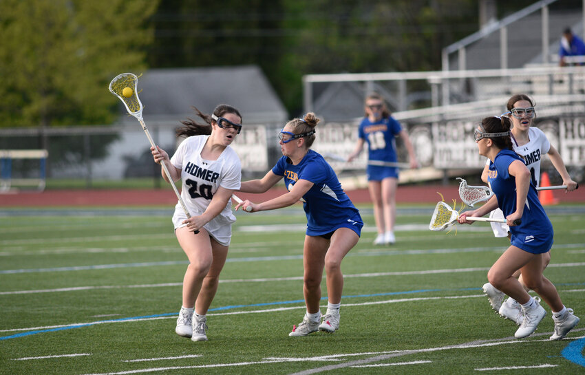 Homer's Maria Partis, left, looks to dodge a double team from Cazenovia/Hamilton defenders Tuesday night at Homer High School. Partis went for seven goals and two assists in the Trojans' 19-10 win.