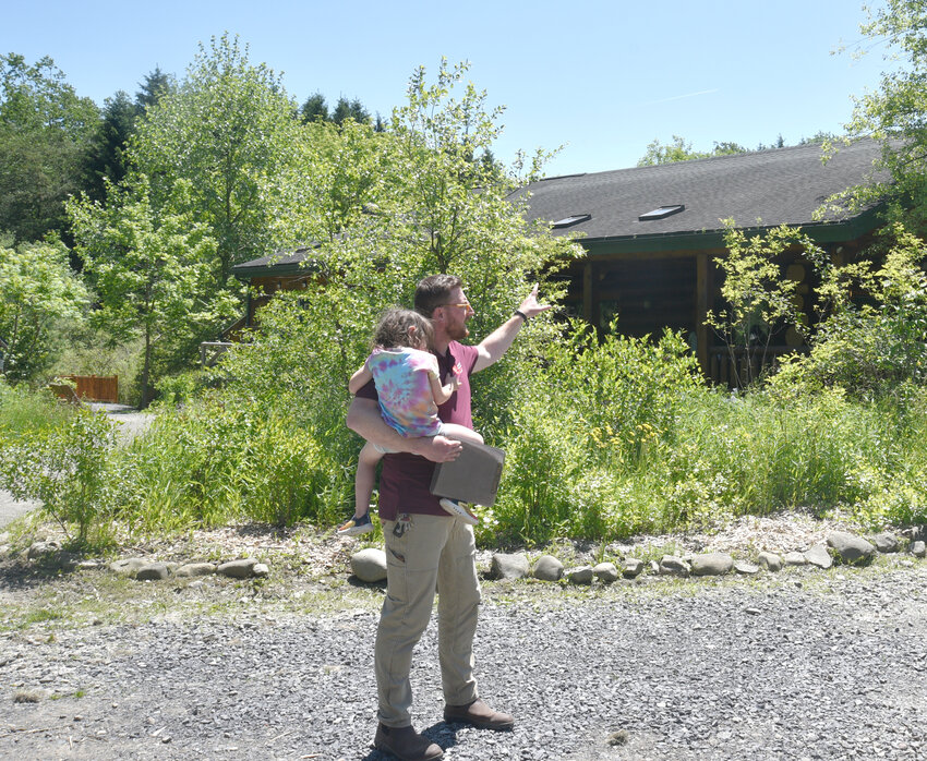 Lime Hollow Nature Center Director Ilya Shmulenson, holding his 3-year-old daughter Rita Shmulenson, explains where new solar panels are going on Lime Hollow's visitor center, which received $250,000 from the state to do so.