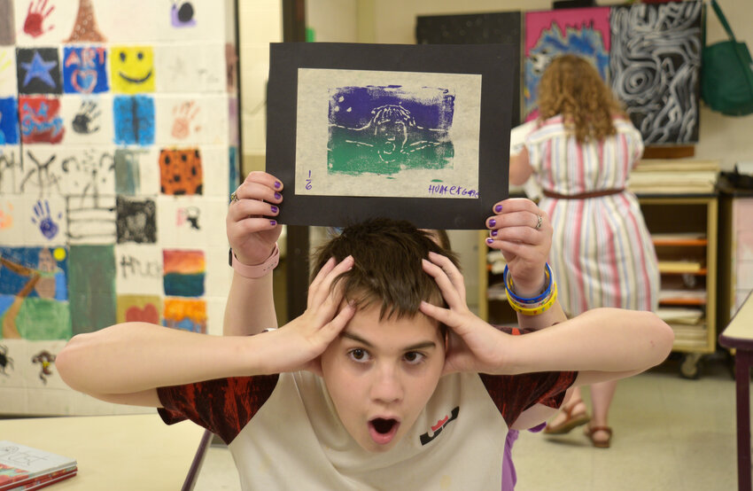 Sixth-grader Hunter Gage re-creates the pose he used for his ink print self-portrait.