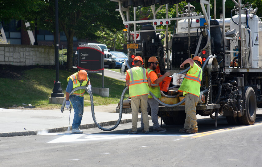 A crew paints road markings Monday on Broadway in Cortland, part of a ummer construction project to improve pedestrian safety on the street dividing SUNY Cortland's east campus from its west campus. Broadway is expected to re-open at mid-day today.