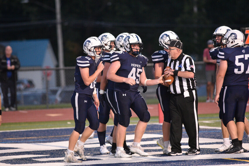 Homer's Alex Votra, center, hands the ball to the official after scoring a touchdown Friday night at Homer High School.