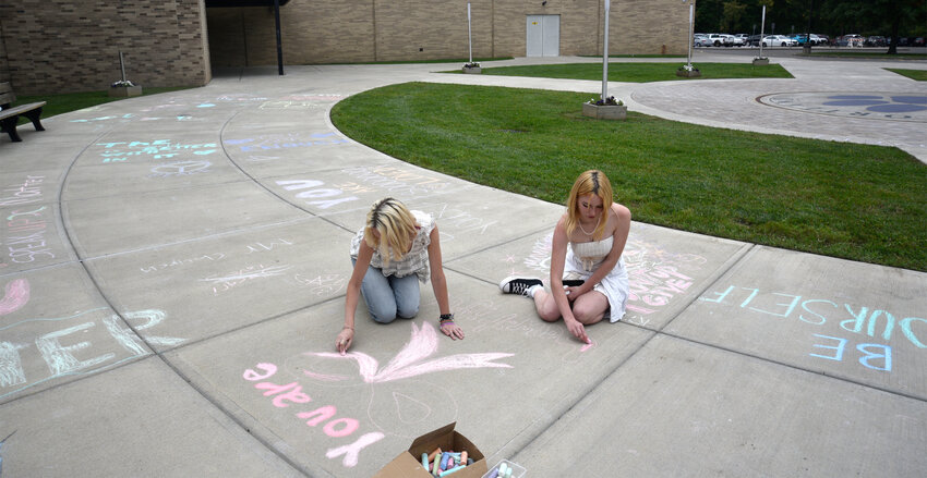 Gabi Hooko, an 11th grader at Cortland High School, and Liz Scanlon, a 10th grader, chalk the walk outside the high school Wednesday as part of National Suicide Prevention Month.