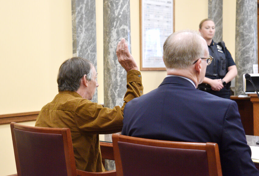 David Storie raises his hand as he takes an oath prior to pleading guilty Thursday morning to second-degree manslaughter, a felony, in the death of his son. His lawyer, Mike Karchak, is seated to his right.