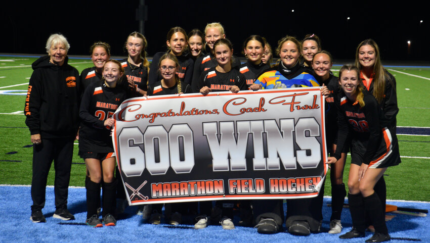 The Marathon field hockey team poses with coach Karen Funk's 600-win banner following a 2-1 double overtime win Thursday at Scarry Athletic Complex.