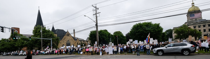 Locals line up at Courthouse Park in Cortland with signs and flags to protest the Trump administration Saturday.