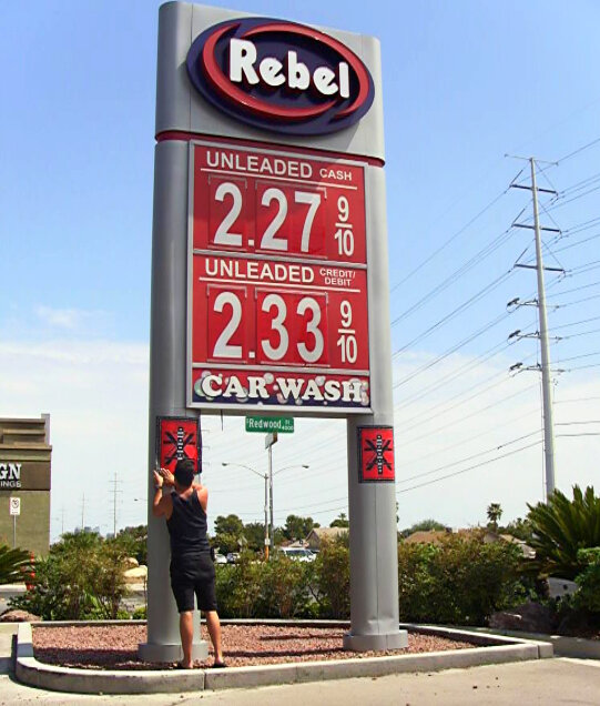 Zoren X. Cruz of Dryden puts up a poster at a Rebel gas station as part of a guerilla art project, posting 268 posters in three weeks across the continental United States.