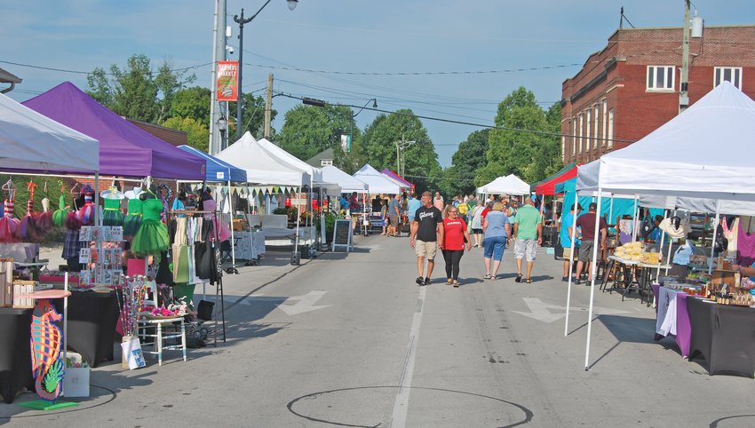 Customers walk along the row of booths at the Crawfordsville Farmers Market on Pike Street.
