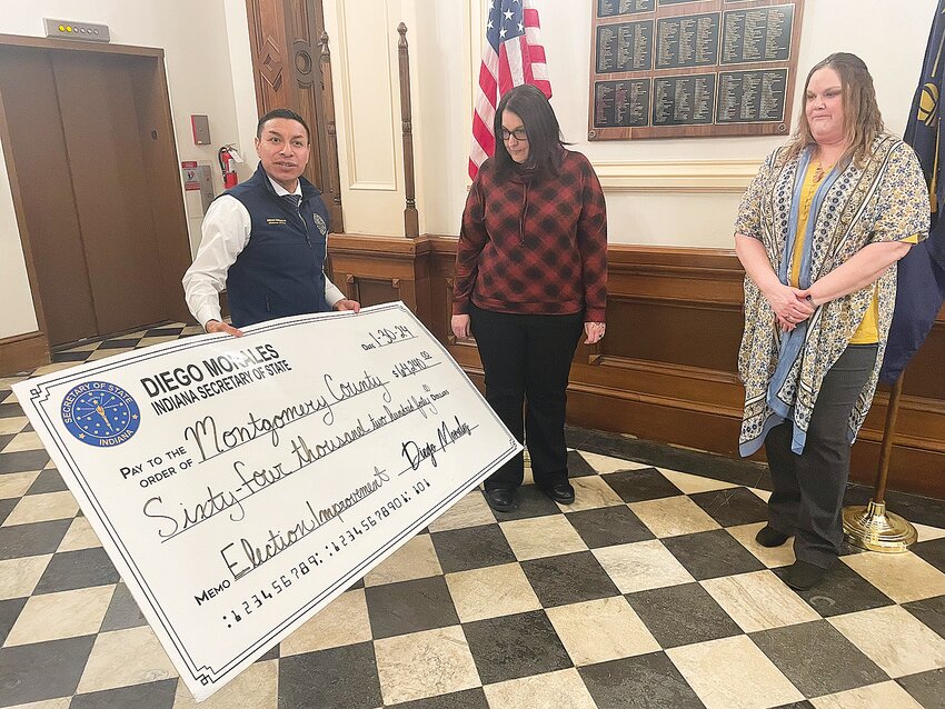 Secretary of State Diego Morales, left, holds a ceremonial check for $64,240 to be awarded to the Montgomery County Clerk&rsquo;s Office. Accepting the award is election coordinator Cassandra Jett, center, and Montgomery County Clerk Leah Denbo. The funds will be used to purchase election equipment.
