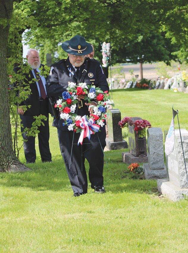 Aaron Clapp, son of fallen New Richmond Town Marshal Mark Clapp, carries a memorial wreath to his father's grave at New Richmond. Clapp died in the line of duty in December 2003.