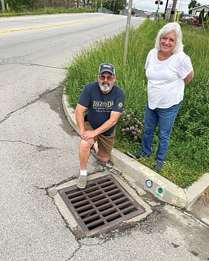 Cindy Woodall, Friends of Sugar Creek Executive Director, and Randy Wheeler, FSC board member, show an identified &ldquo;Adopt a Storm Drain&rdquo; &mdash; one of approximately 2,500 in Crawfordsville. Residents are encouraged to participate in keeping drains clear to improve nearby Sugar Creek and its watershed.