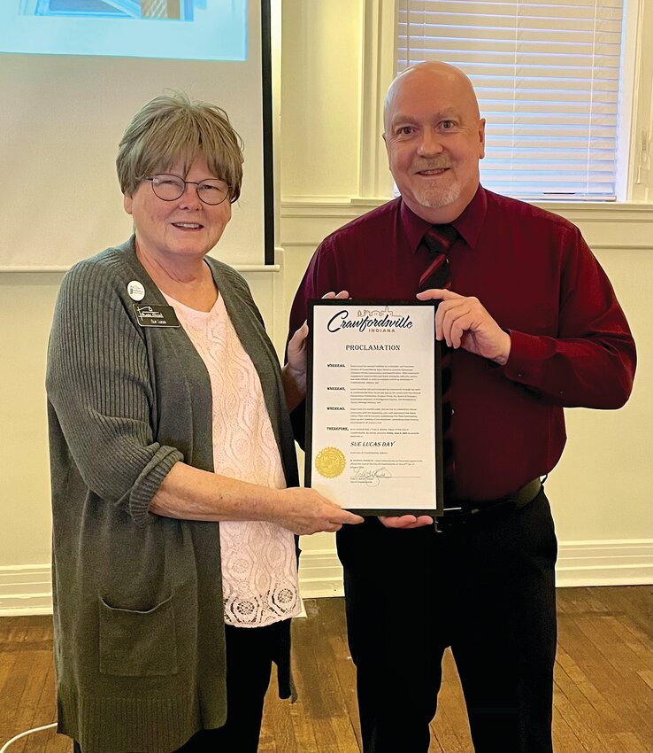 Photo Provided  Sue Lucas, left, and Crawfordsville Mayor Todd Barton pose with the official proclamation that June 6 be declared Sue Lucas Day. The long-time director of Crawfordsville Main Street has retired and Jami Harrington has been named her successor.
