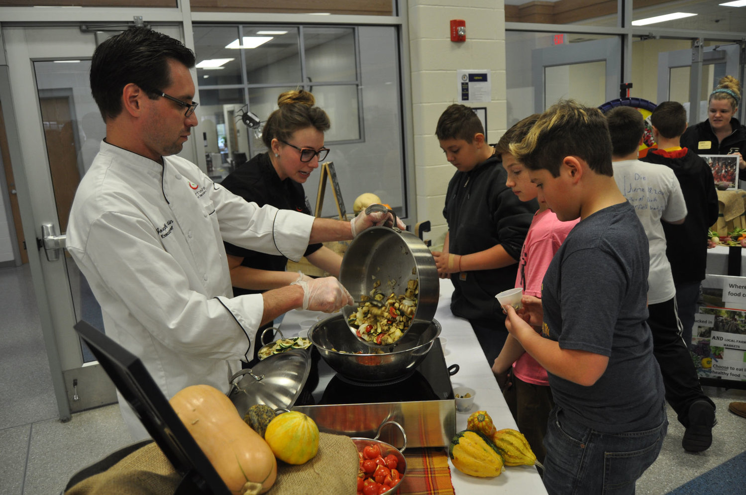 Chartwells chef Joseph Peretin scoops Ratatouille out of a pan as resident dietician Tarrah McCreary speaks to students Friday during the Farm to School event at Crawfordsville Middle School.
