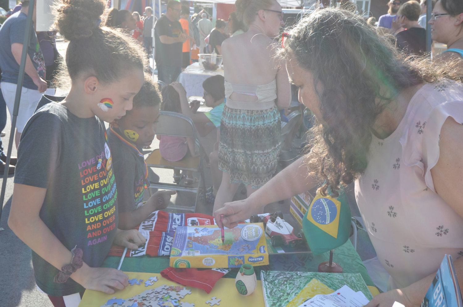 Ivette de Assis-Wilson shows a map of Brazil to Brandon and Jozy Hudson Saturday during Humans United for Equality's Celebration of Unity at Pike Place. Countries around the world were represented at the festival.