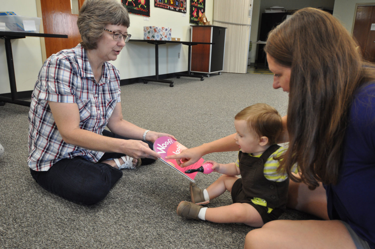 Karen Record, left, holds a book as 11-month-old Robbie Bernhardt and his mother, Melissa, point to a picture during Baby Story Time at the Crawfordsville District Public Library. Record is beginning her 40th year working at the library.