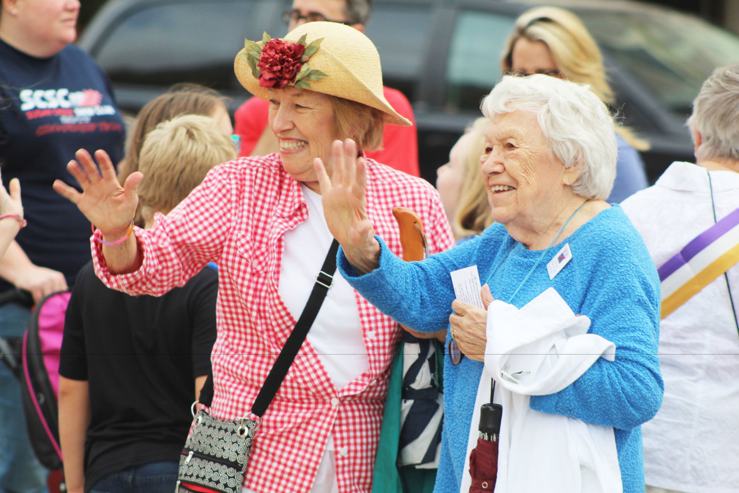 League of Women Voters members Sheridan Hadley, left, and Margy McCafferty wave before a march to commemorate women's suffrage Monday outside the Montgomery County Courthouse.