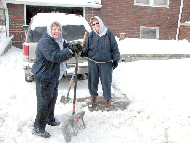 Kay Francis (left) and Andrea Hudson take a break Wednesday from digging their driveway out from under a sheet of ice.