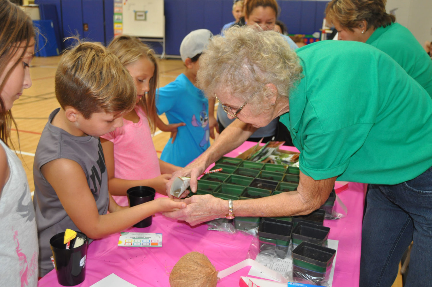 Montgomery County Master Gardener Anita Arnold, right, gives herb seeds to Logan Lowe Tuesday at Nicholson Elementary School. The Master Gardeners showed families how to plant herbs to kick off National Farm-to-School Month.