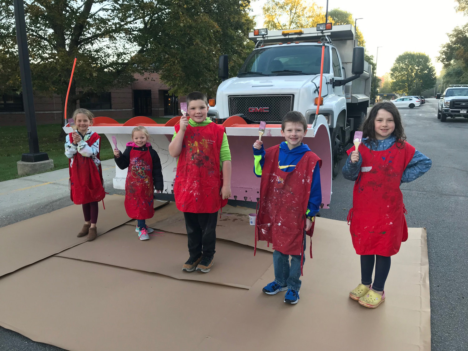 A second group of students stand in front of a plow before they begin painting a Christmas scene.