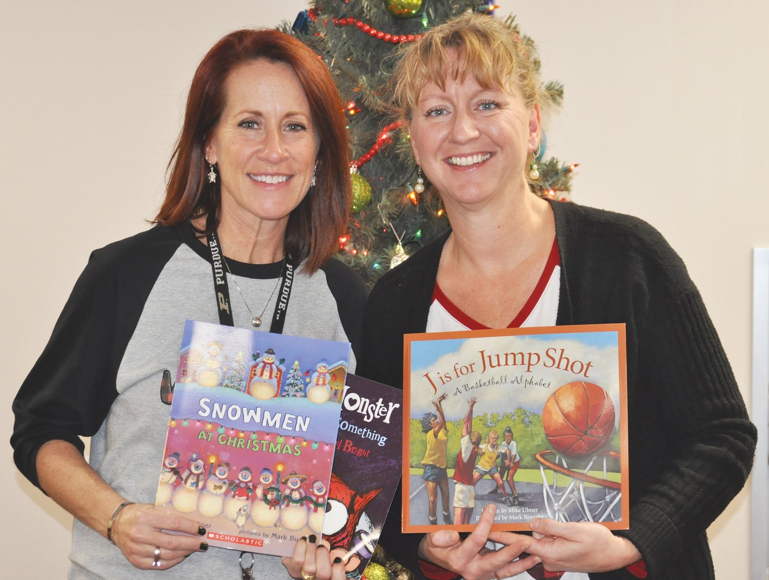 Amber Rohr, left, and Amy Hensley hold some of the books they were able to purchase with the help of a grant.