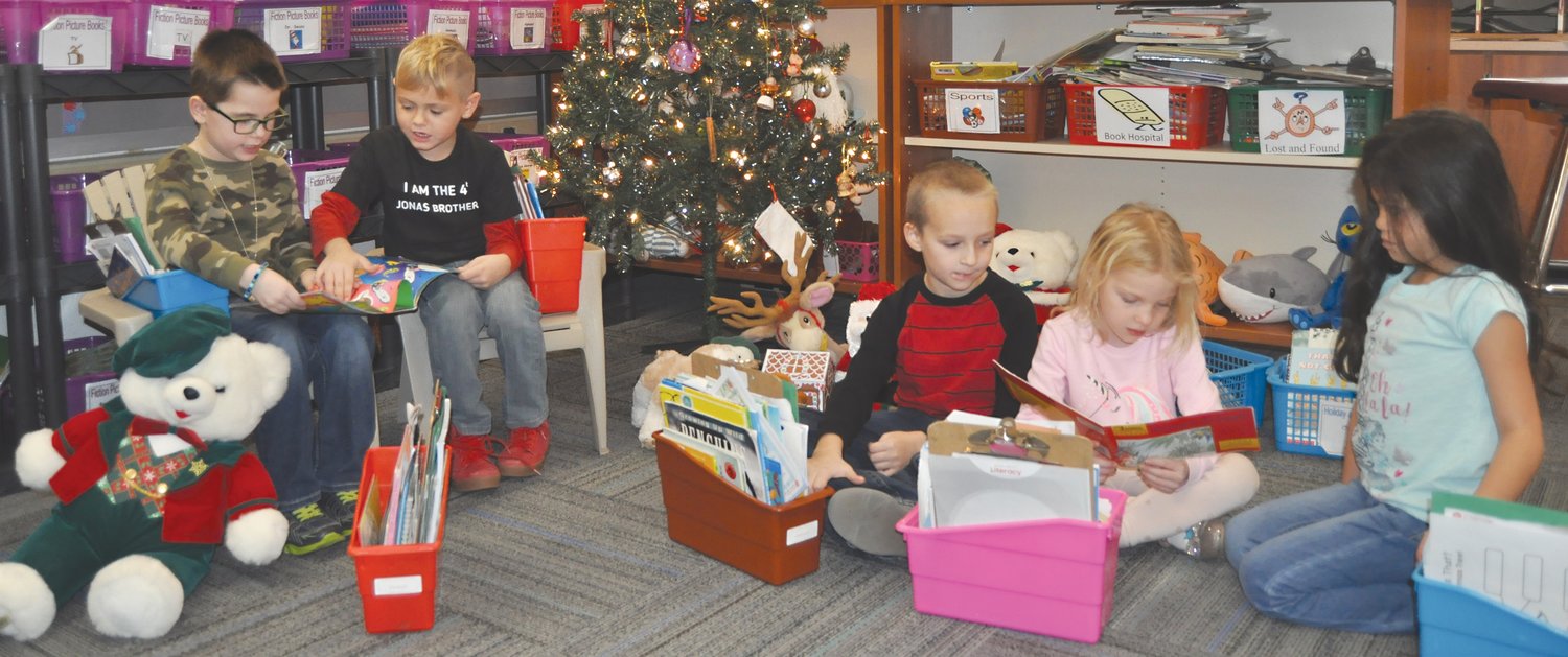Caleb Archer, Hank West, Jackson Kelso, Aynslee Campbell, and Sariah Toves read by the Christmas tree before lunch.