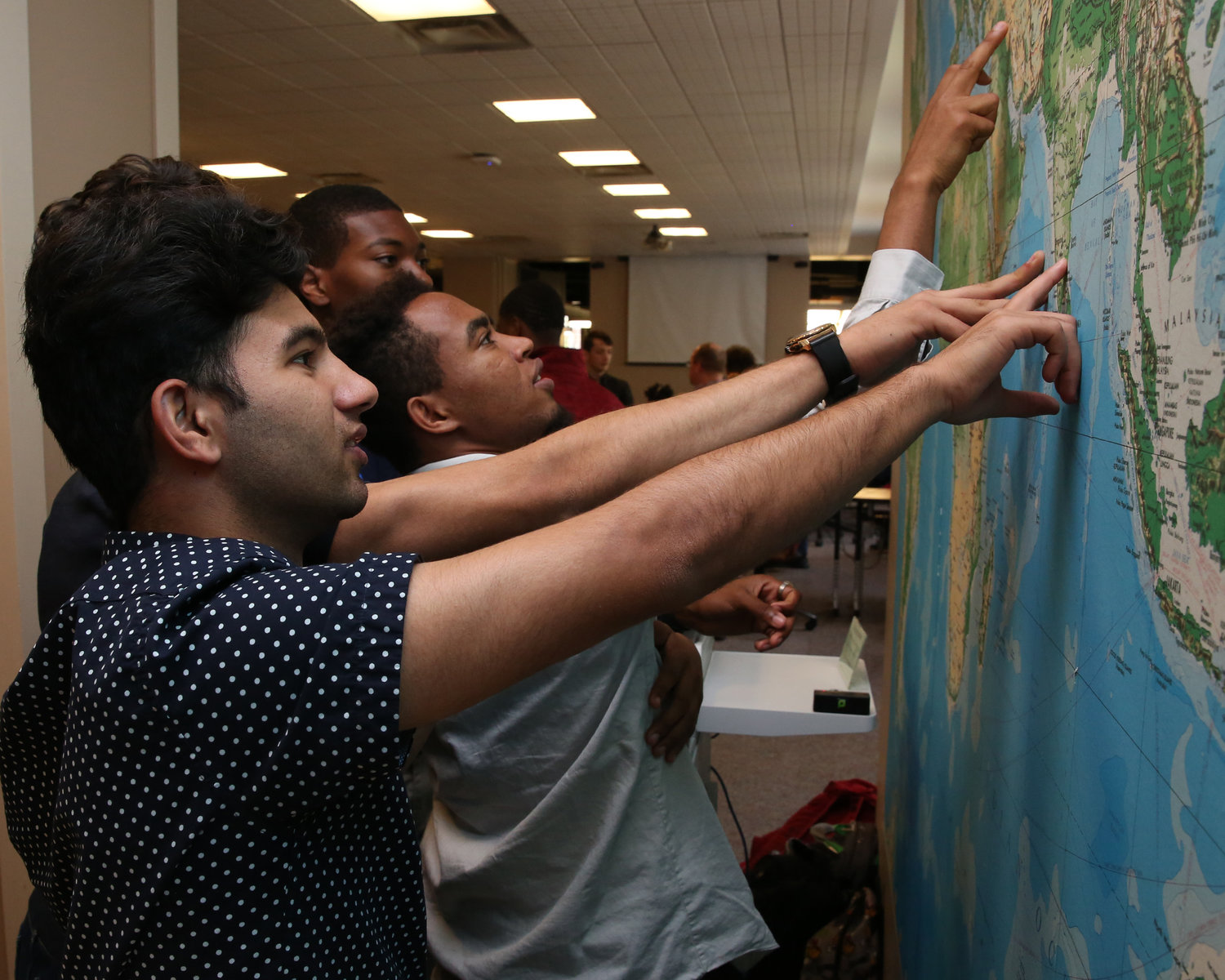 Wabash College students Eugene Bhattanai, Shewa Gared ’23, and Malik Barnes ’23 plot points on the map in the Lilly Library.