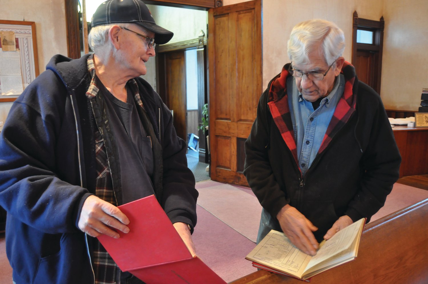 Bill Glover, left, shows Don Cumbow name listed in an attendance book for Osborn Prairie Christian Church. The men's families attended the church.