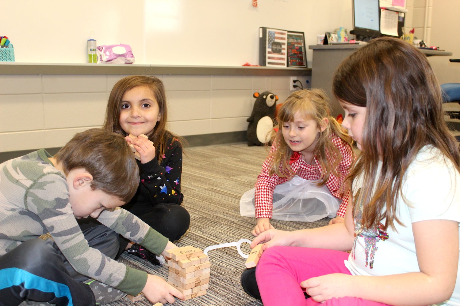 Students Rylin Tyrrell (from left), Abby Tapin, Odette Leaming and Finley Kunley assemble a tower with 100 blocks, each with a number or word written on them, Friday at Sommer Elementary.