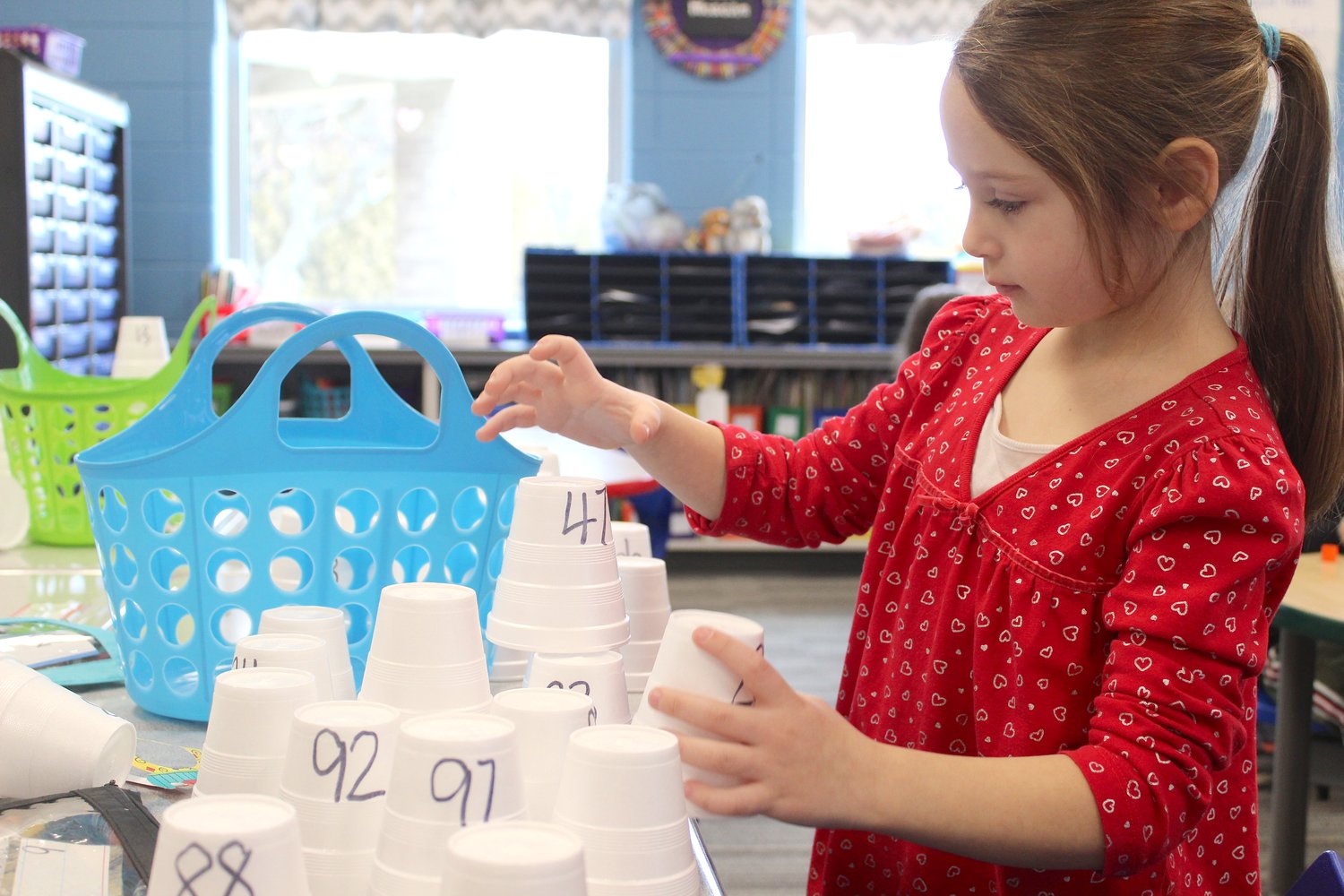 Kindergarten student Arya Steward builds a pyramid of cups with numbers one through 100 Friday at Sommer Elementary.