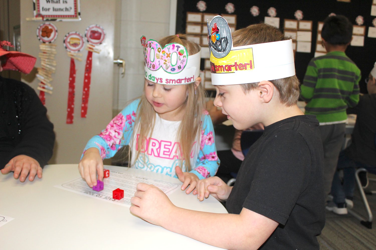 Emma Bishop, 7, left, and Gabriel Webb, 7, roll dice and record their totals as they make their way to 100 during the 100th day of the 2019-20 school year at Hose Elementary.