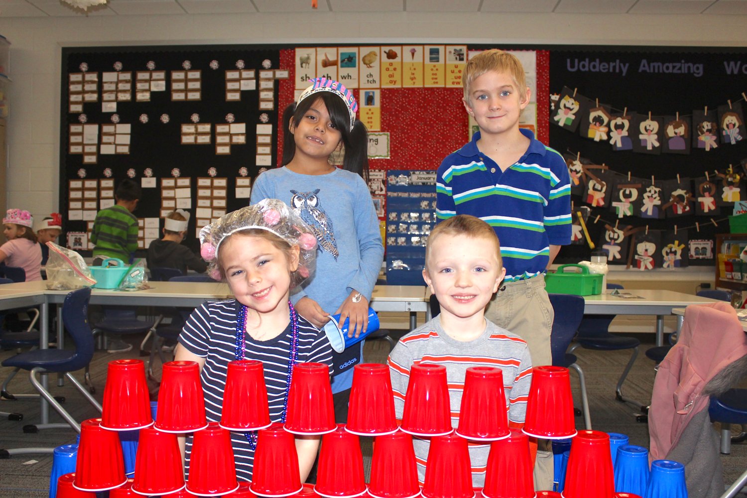 First graders (clockwise fromleft) Addison Blessing, 6, Maria Elizalde Castillo, 7, Rylen Roche, 7, and Ethan Harshman, 7, pose proudly with their 100-cup pyramid Wednesday at Hose Elementary during their 100th day of school.