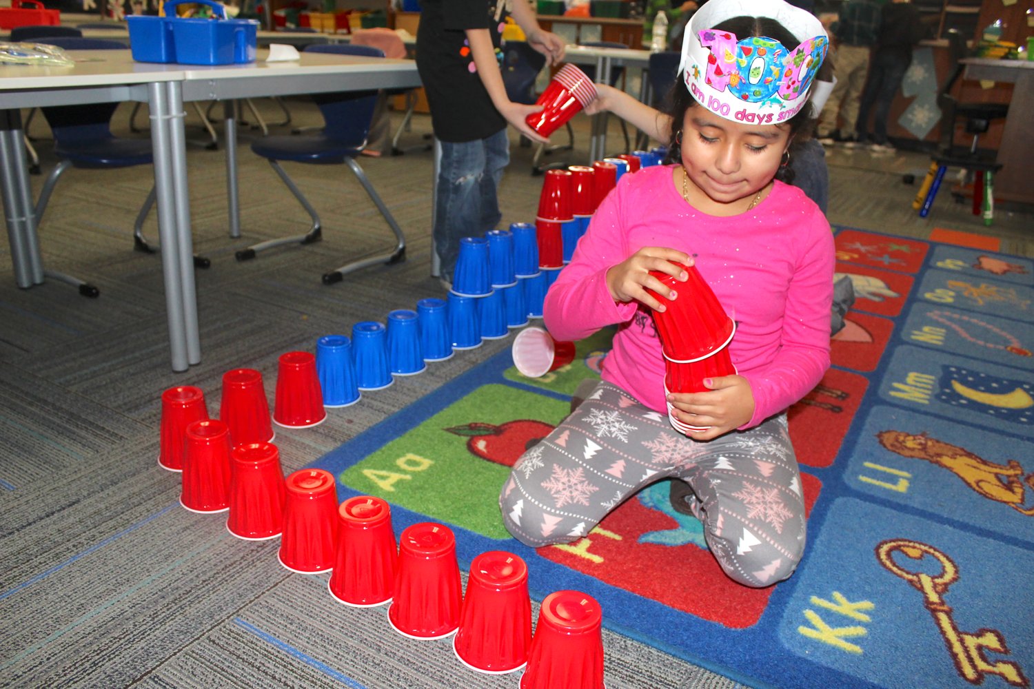 Paola Carrion, 7, uses her 100 cups to build a fort Wednesday at Hose Elementary during her 100th day of school.