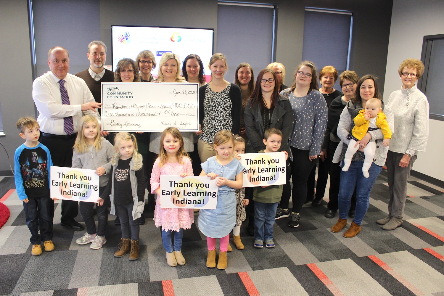Mayor Todd Barton, from left, Rainbows and Rhymes Director Rachel Campbell and Montgomery County Community Foundation Executive Director Kelly Taylor hold a grant check for $100,000 made out to Rainbows and Rhymes and Hand-In-Hand preschools Thursday on the third floor of the Fusion 54 building.