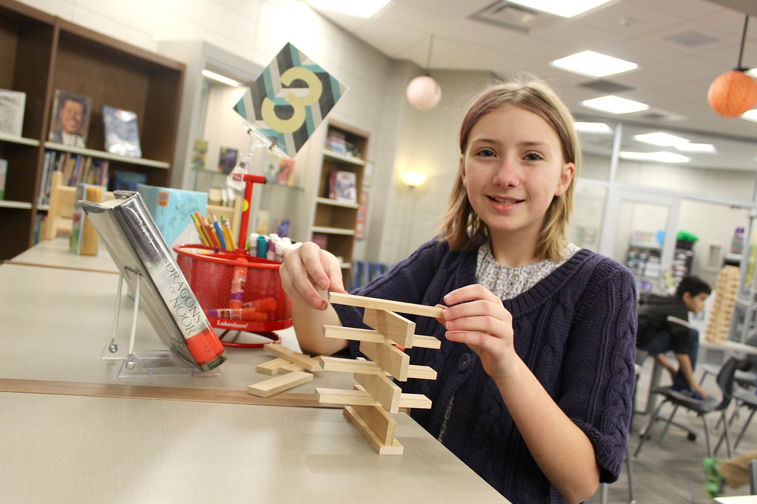Elizabeth Brooks, 11, attempts to build a tower Thursday in the Pleasant Hill media center with a unique design.