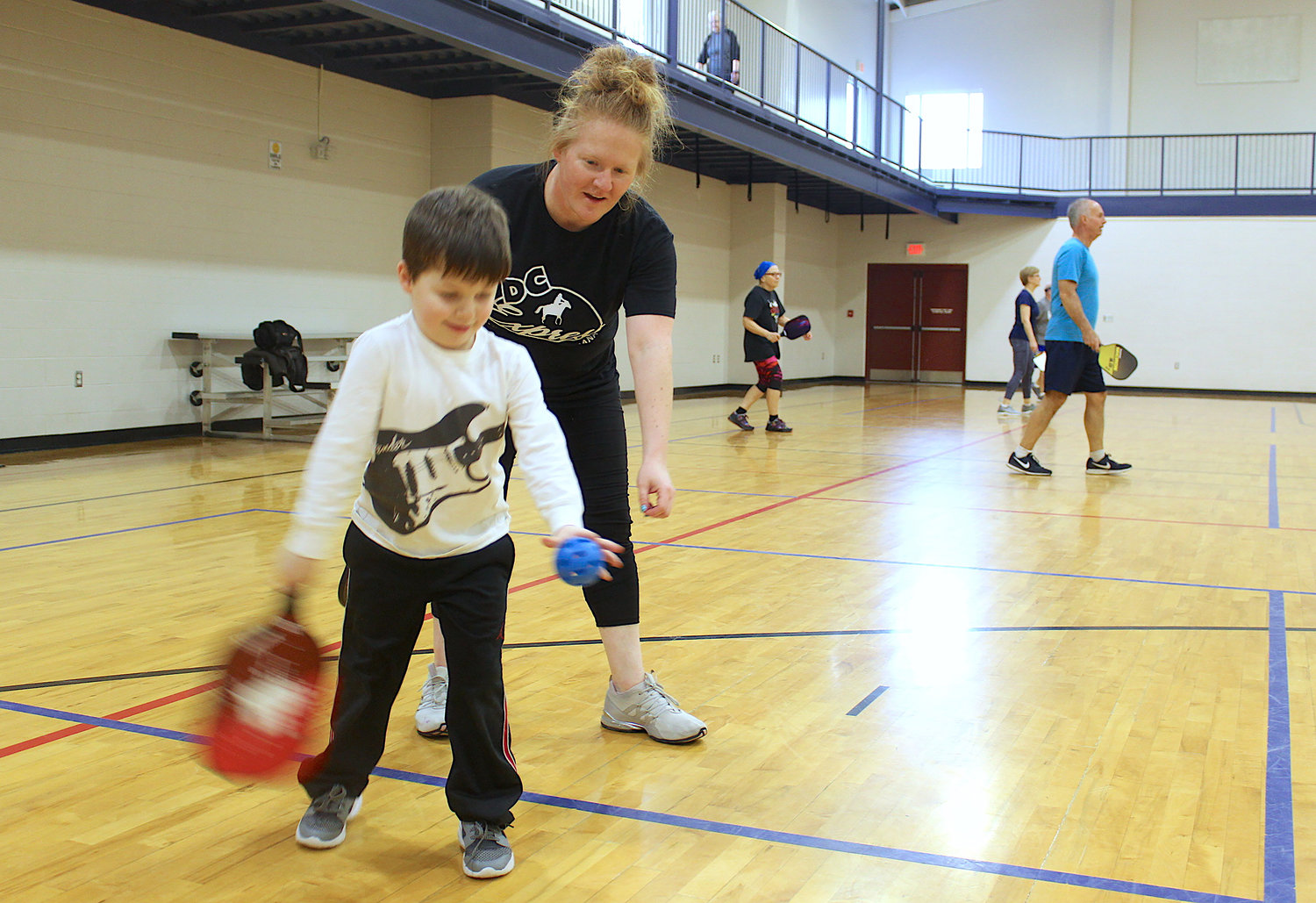 Dominique Fruits takes a moment to teach the finer points of Pickleball to son Noah, 4, Friday at Crawfordsville Parks and Recreation.