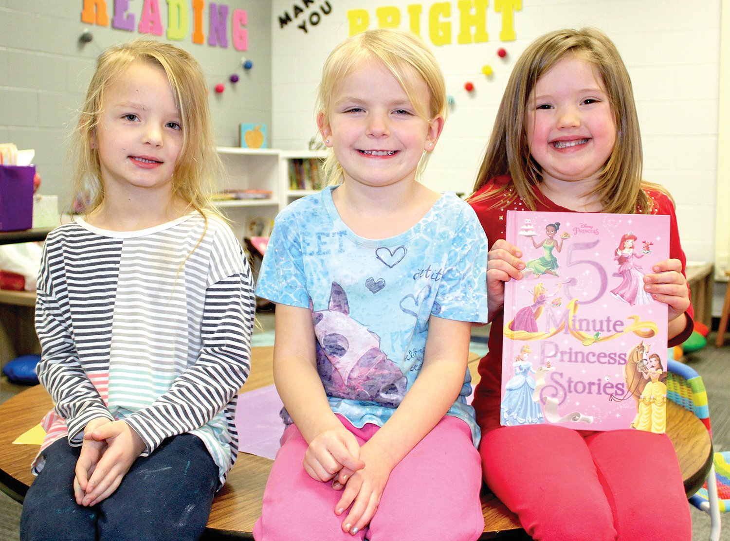Showing off the story they just heard, preschoolers Lux Highland, from left, Vera Carrell and Bailey Rhodes pose for a picture Wednesday at Little Mountie Preschool.