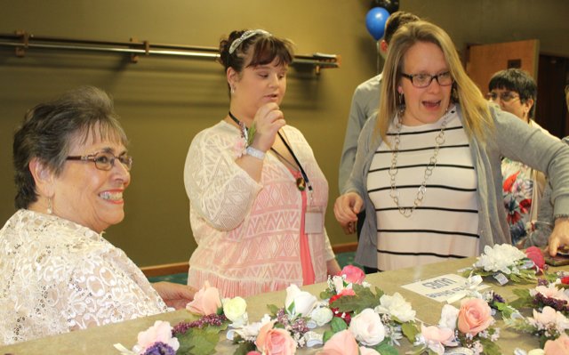 Roberta McBride, from left, Madison Stover and Erin Gilland visit the corsage table Friday at New Hope Christian Church.