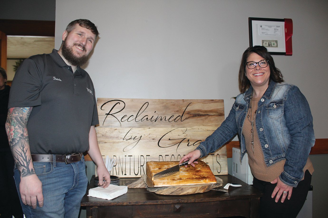 Travis and Jami Harrington of Reclaimed by Grace cut a cake designed to mimic a block of wood Monday during the shop's official grand reopening.