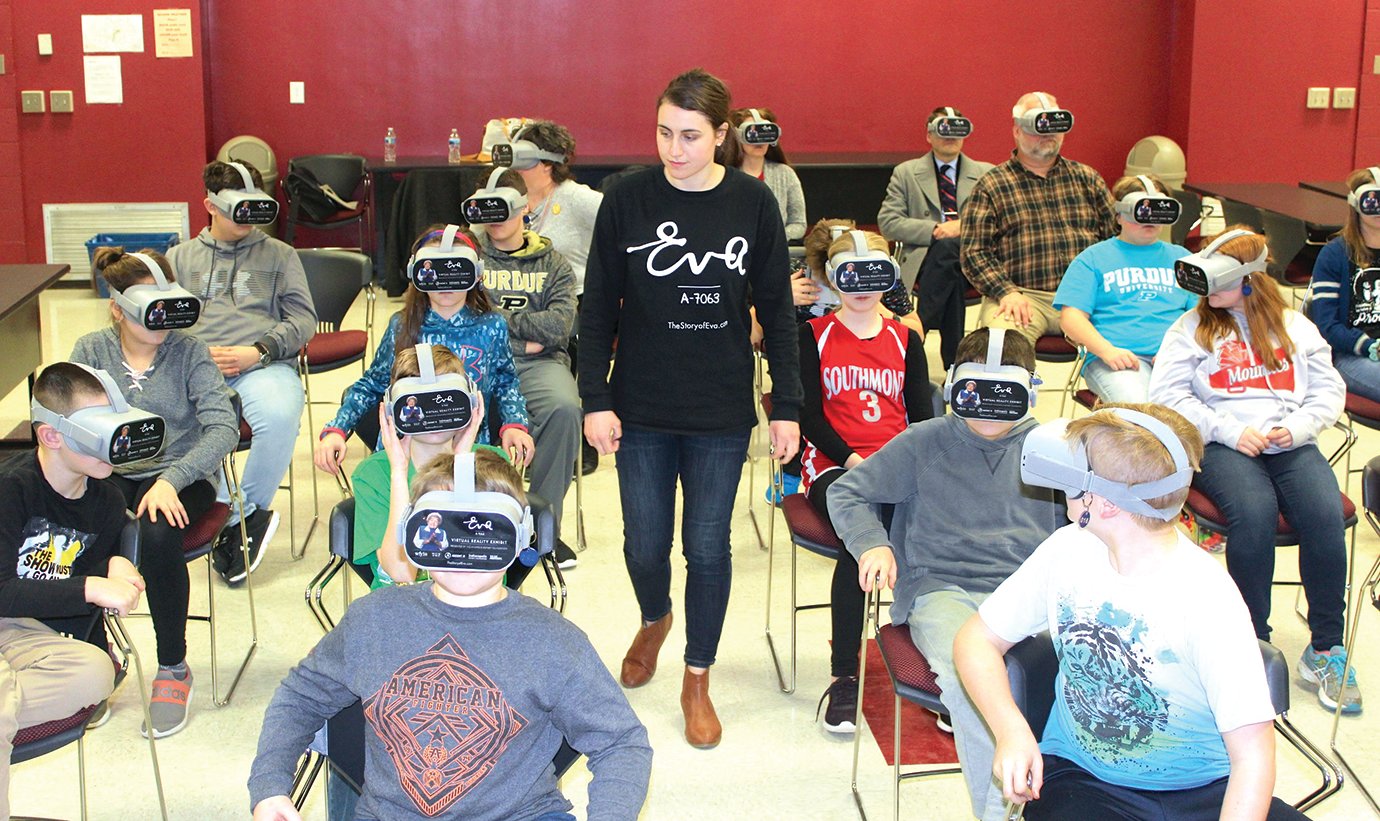 Jessica Chapman of WFYI Indianapolis, center, walks the aisles of the LGI Classroom inside Southmont High School on Monday, ensuring an optimum virtual reality experience for participants of the Eva Education Program. Title I Coordinator Anna Roth, Superintendent Shawn Greiner and science teacher Tony Gonczarow, background, joined 20 middle school students for a virtual reality tour of Auschwitz and Auschwitz-Birkenau, featuring both historic and modern-day imagery.