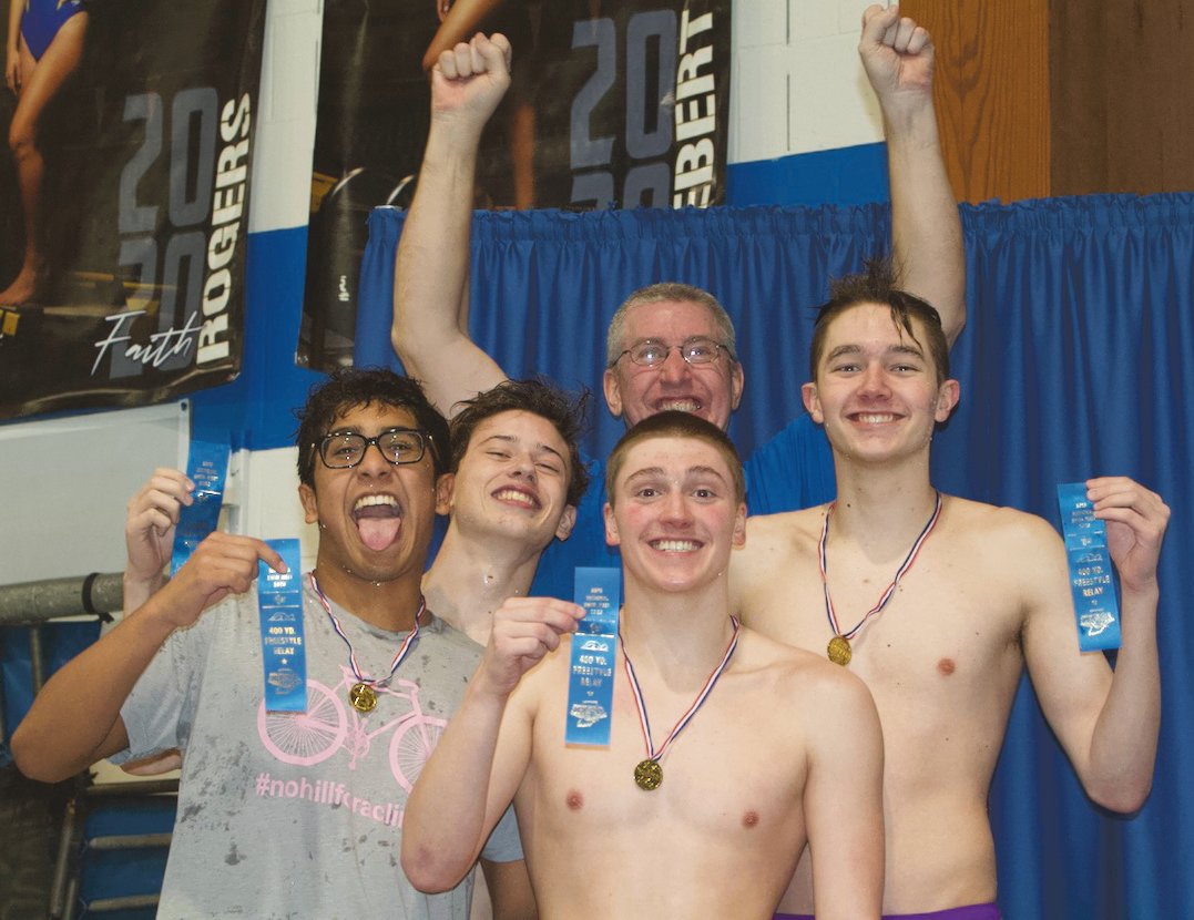 Thristan Callejas, Evan Chaney, Ben Brown, and Jack Pendleton celebrate their sectional win in the 400 freestyle relay with Crawfordsville coach Kevin Hedrick on the podium.